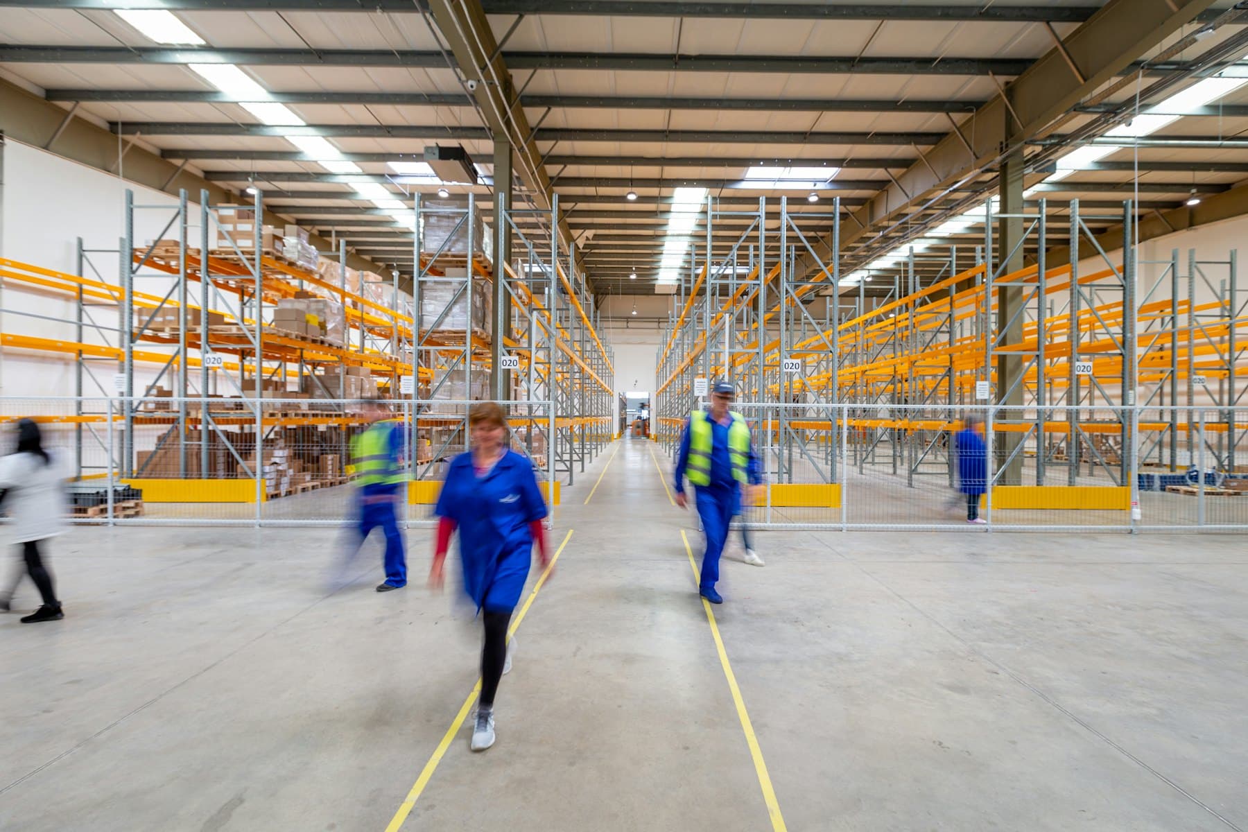 Équipe logistique circulant dans un entrepôt aux rayonnages orange